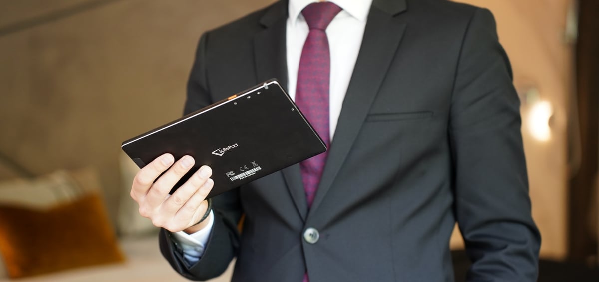 A man in a suit holding a SuitePad tablet